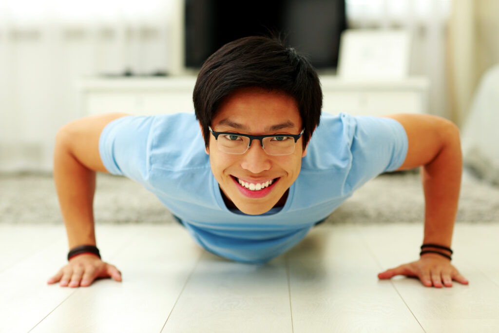portrait of a happy young man doing push ups in the living room at home