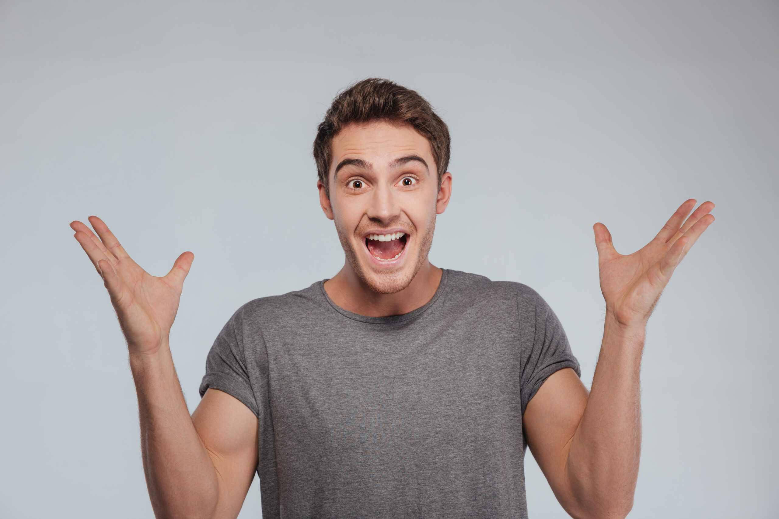 graphicstock portrait of an excited casual man standing with raised hands and looking at camera isolated on a white background BIVCFD7d3e scaled